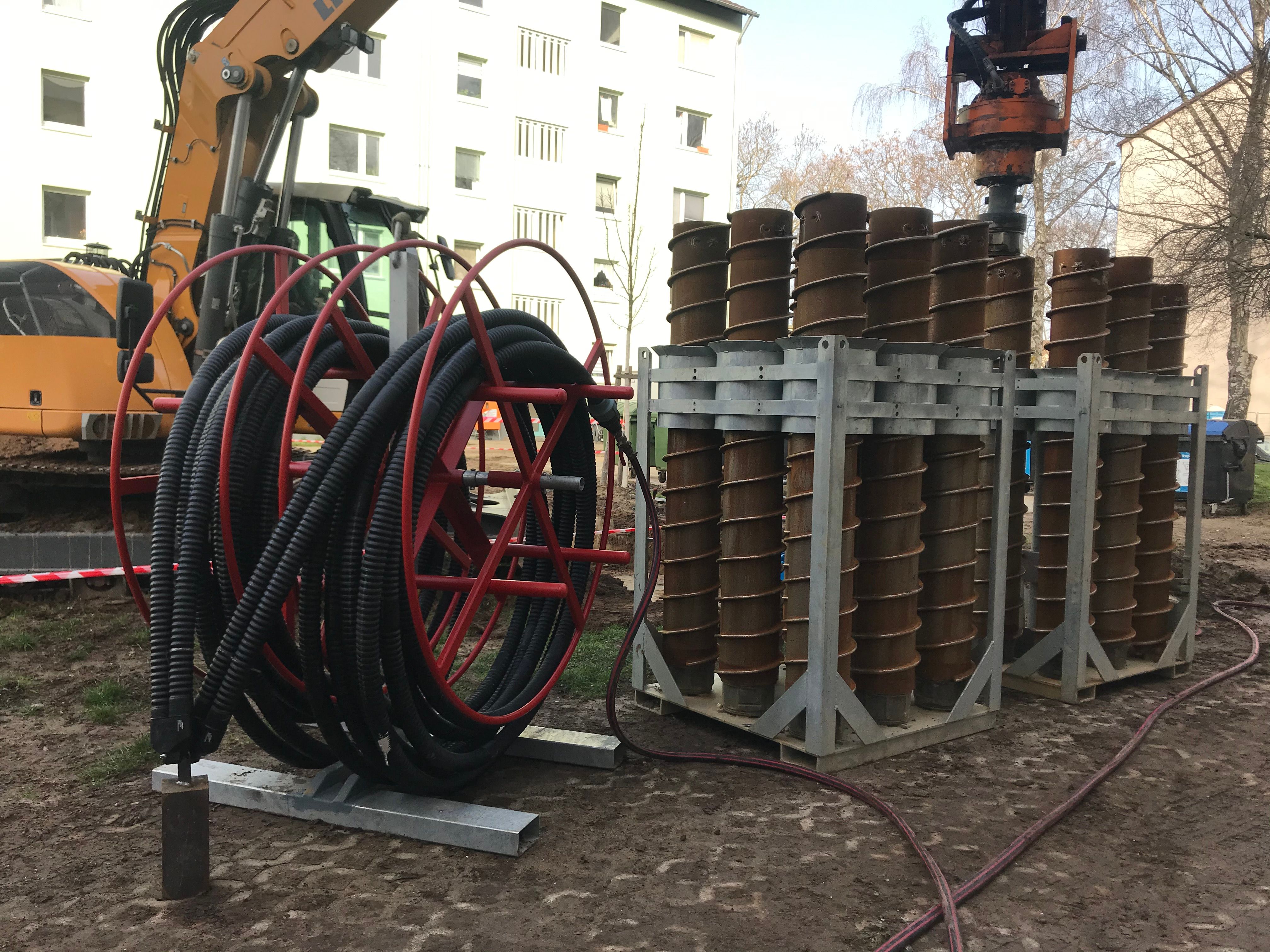 Bild 6a–c Mehrfamiliengebäude (Baujahr 1963) mit Mehrquellen- Wärmepumpensystem in Karlsruhe Durlach: Kombination einer Außenlufteinheit (a) und eines kleiner dimensionierten Erdsondenfelds (b) sowie Bohrschnecken und Doppel-U-Sonden bei der Installation (c)