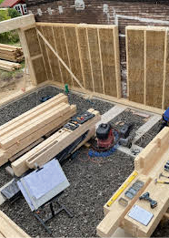 Bild 4 Reihenendhaus in Berlin; a) Wände und Dach sind als Holzmodule mit Strohdämmung ausgeführt b) die Holzfassade wurde durch natürliches verkohlen witterungsbeständig gemacht. Die Giebelseite wurde aus Abbruchklinkern erstellt. (Quelle: Spreeplan)
