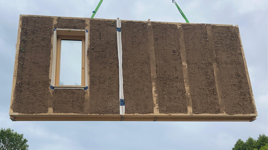 Bild 8 Einheben eines vorgefertigten Wandelements mit Fenster; eine erste Lehm- und Kalkschicht wurde bereits in der Vorfertigung angebracht (Quelle: Alessandro Tonnarelli)