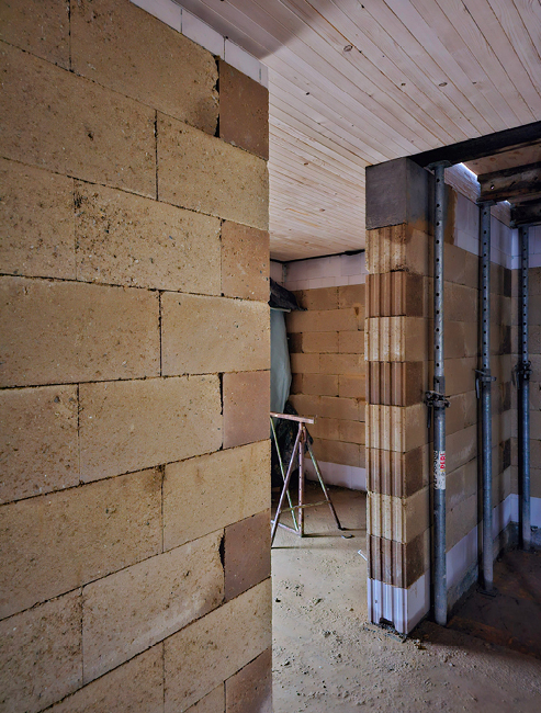 Bild 5 Tragende Lehmsteinwände mit Havarieschutz in der unteren Steinlage in Form eines Kalksandvollsteins, kombiniert mit einer Brettstapeldecke im Wohnungsbau (Quelle: Mendler)