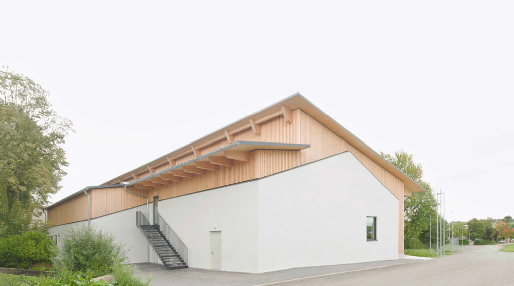 Bild 7 Mehrzweckhalle Ingerkingen, a) Ansicht Südfassade, b) Nordwestansicht (Foto: Brigida González)